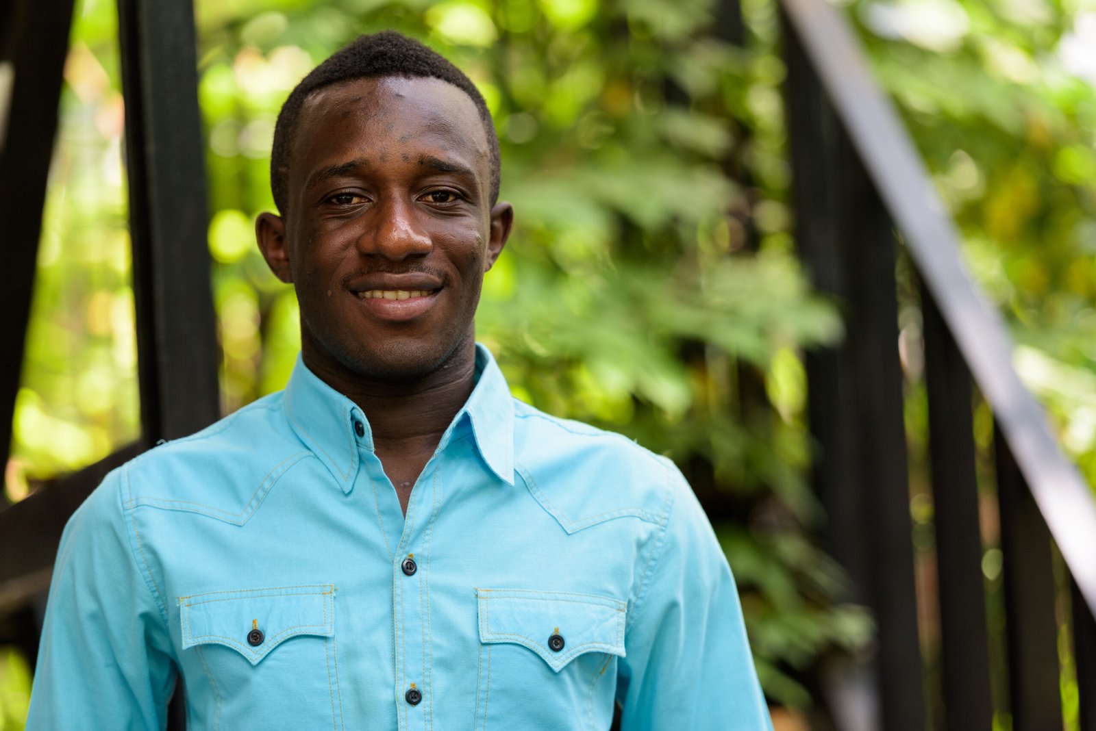 Young happy black African man smiling against modern staircase w